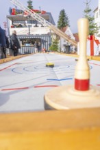 A wooden bowling game at a Christmas market with spectators standing in the background,