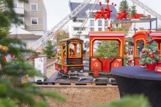 A brightly decorated miniature train with red stars in a festive city setting, Sindelfingen,
