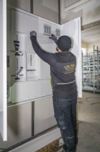 Technician working on a control cabinet, gloves, electrical cables, electrician, new building,