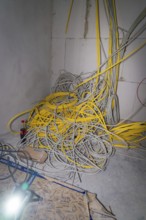 Disordered pile of yellow and gray cables in a corner of a room, electrician, new building, Germany
