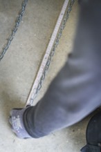 A hand pulls on a chain lying on the ground next to a tape measure, electrician, new building,