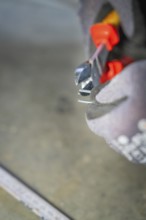 Close-up of pliers cutting wire while a glove-clad hand holds them, electrician, Neubau, Germany