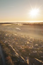 A village under golden sunlight with rays illuminating a warm autumn landscape, Gechingen, Hecken
