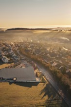 Aerial view of a village in morning fog with autumnal atmosphere and sunlight, Gechingen, Hecken
