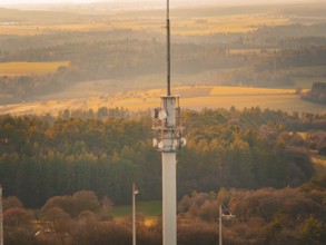 Close-up of a radio tower over a forest and field landscape in warm light, Gechingen, Hecken and