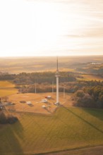 A radio tower stands in the middle of a large field, surrounded by forests at sunset, Gechingen,