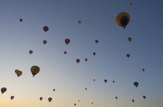 Many hot air balloons float in the morning sky and create a calm and adventurous atmosphere, Göreme