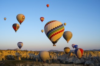 Colourful hot air balloons over a rocky landscape in soft morning light convey a sense of