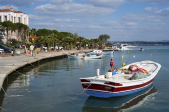 Small boats lie quietly in the harbor on a paved coast under blue sky, Alibey, Alibey Adasi Island,