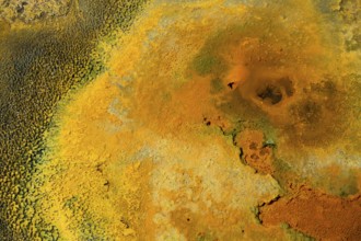 Detailed view of a mineral-rich volcanic landscape in intense shades of orange, geothermal area,