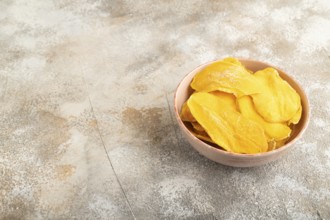 Dried Mango in ceramic bowl on brown concrete background. Side view, copy space. healthy food,