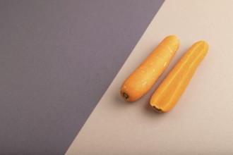 Orange Carrot on beige and gray pastel paper background. Side view, copy space, flat lay. healthy