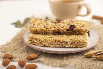 Granola bars with caramel, nuts, flakes in ceramic plate on white wooden background, beige linen