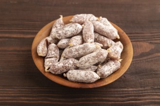 Small smoked Chicken sausages in wooden bowl on brown wooden background. side view, close up