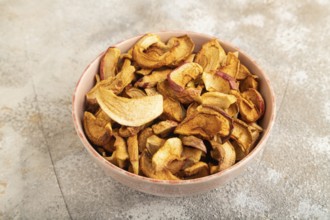 Dried Apples in ceramic bowl on brown concrete background. Side view, copy space, flat lay. healthy