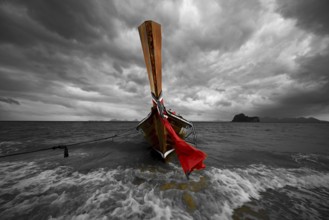 Longtail boat on the beach with dark rain clouds behind it, Koh Ngai island, Andaman Sea, Satun