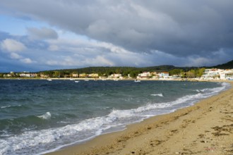 A beach with soft waves, cloudy skies and houses along the coast, beach near GÃ¼zelyali,