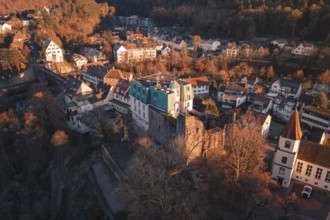 Aerial view of a village with castle and hills in the background, in the evening light,