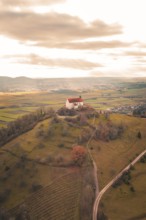 A hill with a church surrounded by vast fields under a dramatic sky, Wurmlinger Chapel, Rottenburg