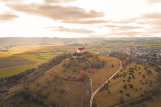 A church on a hill with a wide view of fields and villages under a cloud cover, Wurmlinger Chapel,
