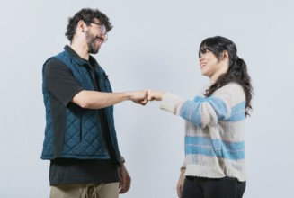 Smiling couple bumping fists, isolated. Attractive couple smiling and bumping fists