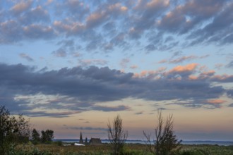 Fishing hut in reeds (Phragmites australis) on the banks of the lagoon, evening cloudy sky,