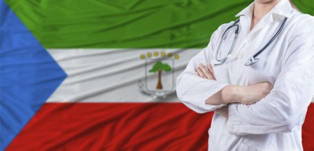 Doctor with crossed arms on Equatorial Guinea flag. Equatorial Guinean health and care concept.