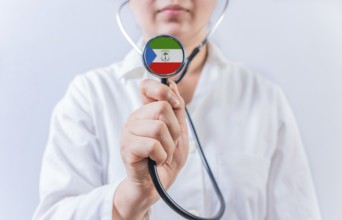 Female doctor holding stethoscope with Equatorial Guinea flag. National health system of Equatorial
