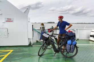 Cyclist with helmet, bicycle tour, e-bike with luggage bags on a ferry, Baltic Sea, Germany