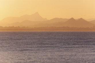 View of the ocean and Byron Bay hinterland at sunset. Mt. Warning, Wollumbin National Park over the