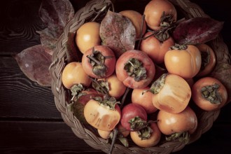 Fresh persimmon in a basket, with leaves, top view, no people
