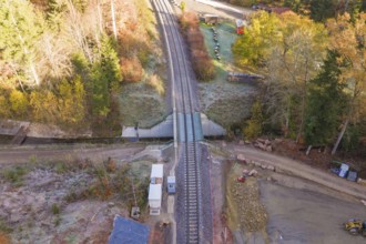 Autumn aerial view of railroad crossing and tracks surrounded by trees, Hermann Hesse Railway bat