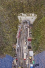Aerial view of a railway tunnel construction site surrounded by green vegetation, Hermann Hesse
