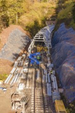 Aerial view of a construction site with railroad tracks and tunnel under construction, Hermann