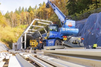 Workers erect a metal structure in front of a tunnel in autumn with crane support, Hermann Hesse