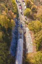 Material transport on a tunnel construction site, nestled in autumn forest from a bird's eye view,