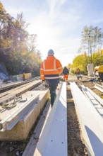 Construction workers in protective clothing walk along a construction site in an autumn scene,