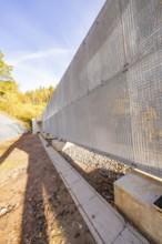 A long metal protective wall along a building area in an autumn landscape, Hermann Hesse Railway
