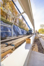 View along a rail line with metal structures under construction and a crane, Hermann Hesse Railway