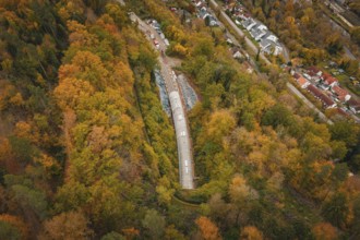 Aerial view of a railway tunnel surrounded by autumnal forest and nearby houses, Hermann Hesse