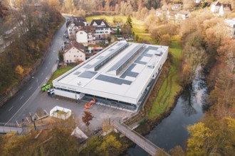 Building with solar panels on the river in an autumnal village, PV at Walther Lindner Sporthalle