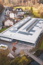 Building with solar panels surrounded by village houses and autumn trees, PV at Walther Lindner