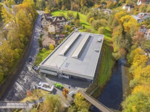 Panorama of a modern building with solar panels, embedded in an autumnal village and river