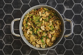 Freshly cooked mushrooms and onions are sautÃ©ed in a large skillet. Green leek add flavor. The