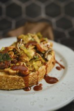 A warm mushroom sandwich is served on a rustic plate, topped with honey mushrooms, enoki mushrooms,