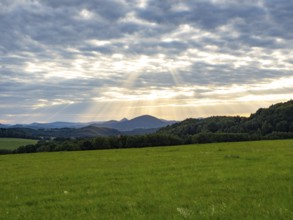 Sunbeams over gentle mountain landscape and meadows, Bohemia, Lusetian Mountains, Czech Republic