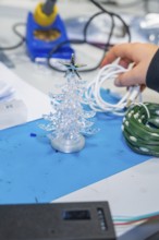 Small plastic Christmas tree on craft table with cable in hand, Jugend Forschungszentrum Nagold,