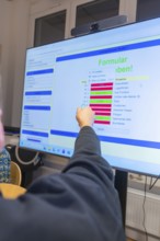 Person pointing at digital forms on a large screen, Jugend Forschungszentrum Nagold, Calw district,