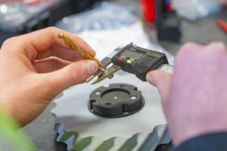 Hand holding caliper and measuring metal gear, Jugend Forschungszentrum Nagold, Calw district,