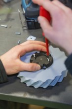 Screwdriver fixes screws to a gear wheel in a workshop environment, Jugend Forschungszentrum